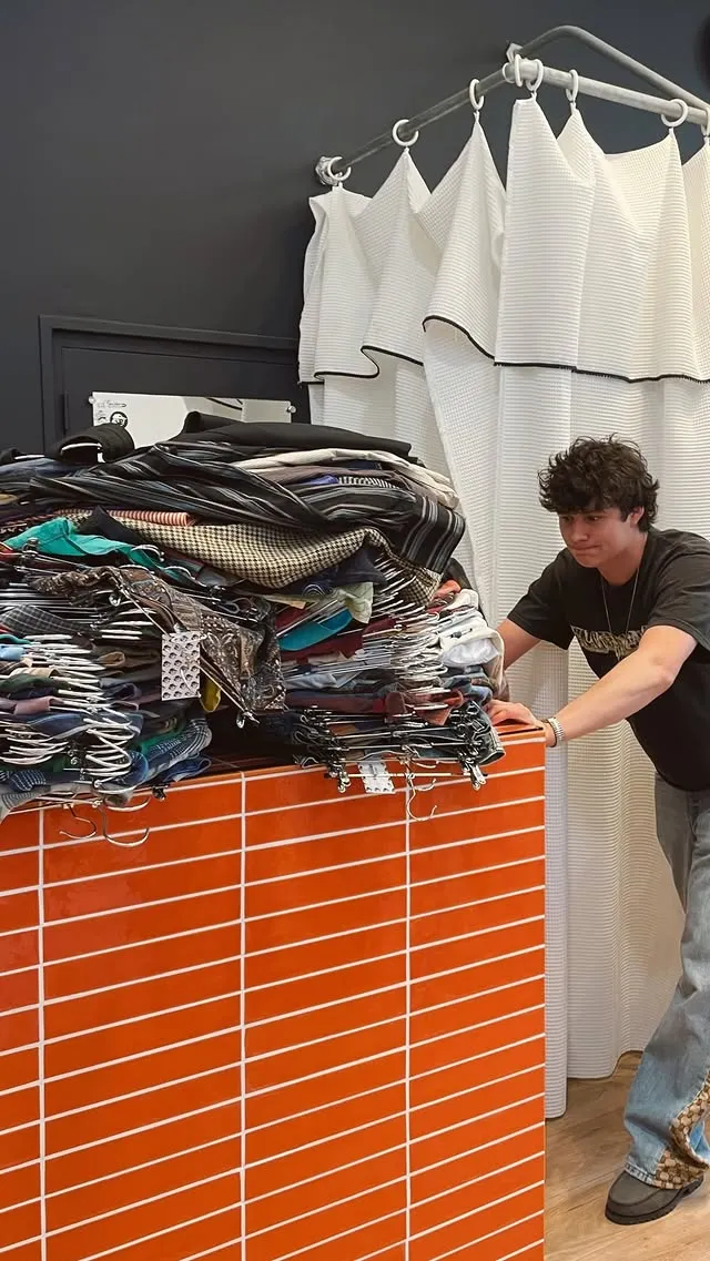 Jour de réassort : piles de vêtements et portants pleins dans la boutique