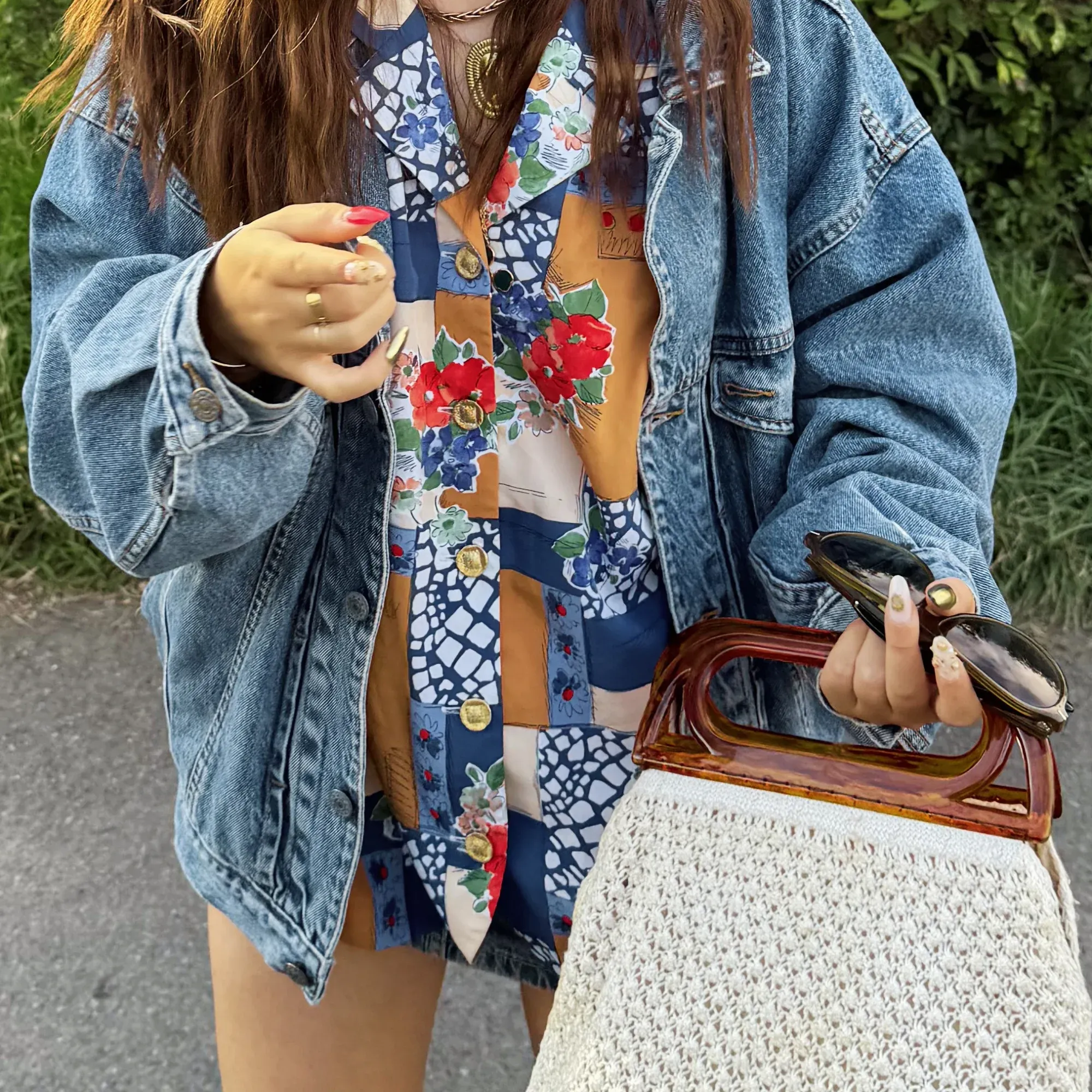 Chemise à motifs portée sous une veste en jean, avec un sac vintage