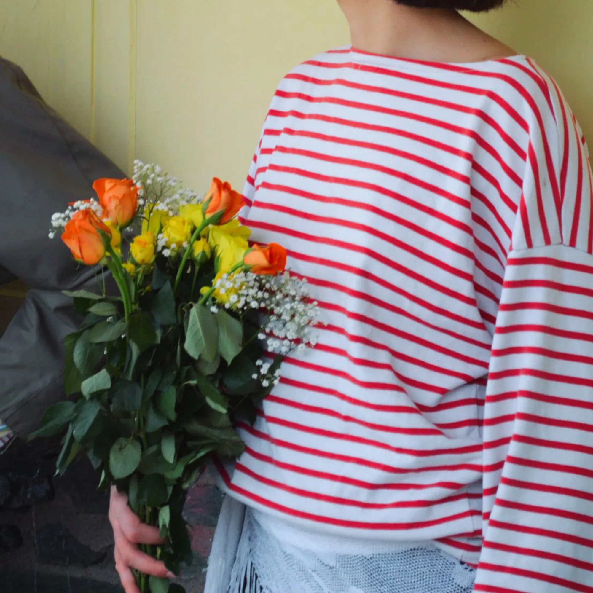 Marinière rayée rouge et blanc portée devant un bouquet de roses